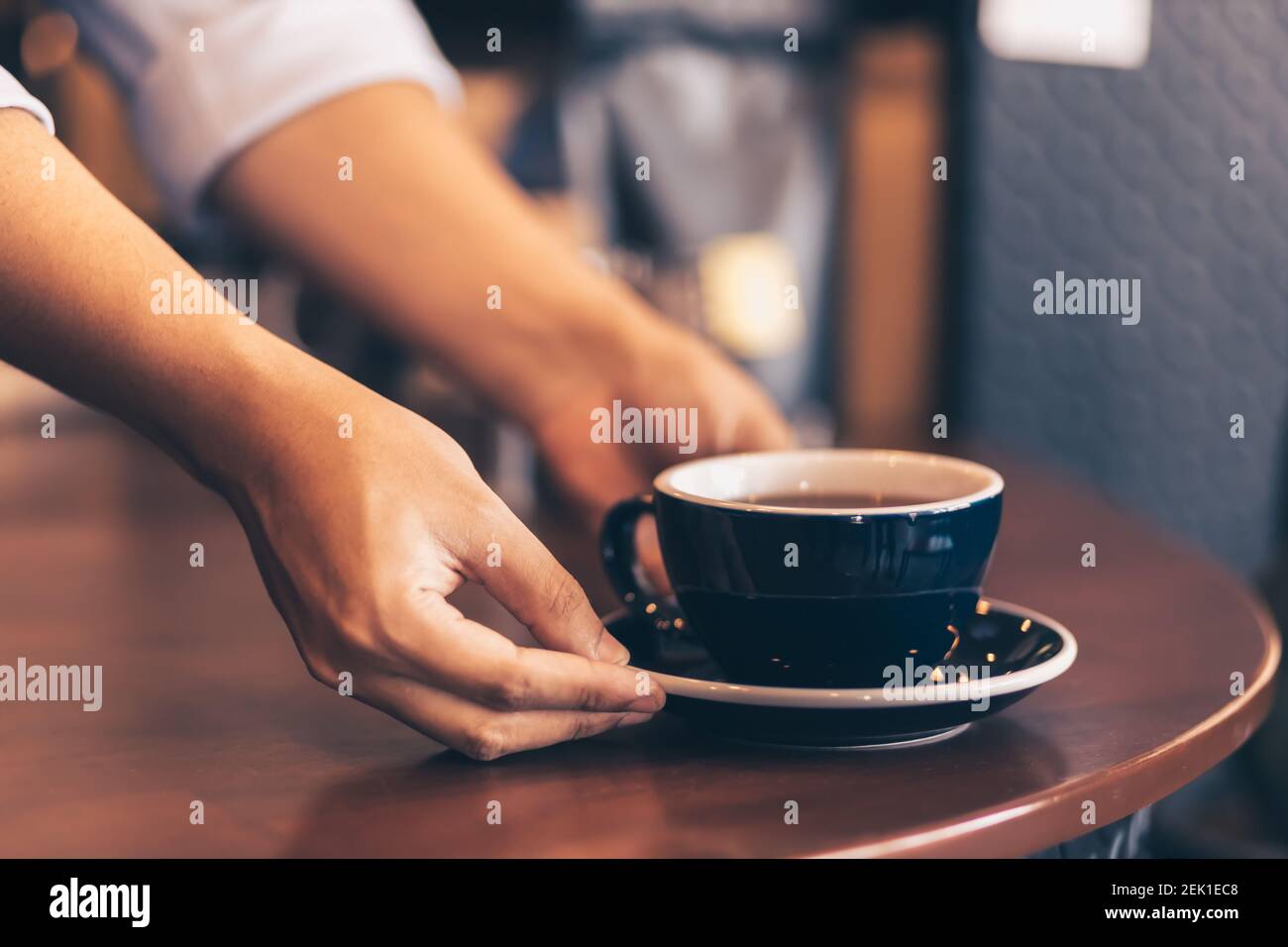 Barista serviert dem Gast im Café einen Kaffee. Stockfoto