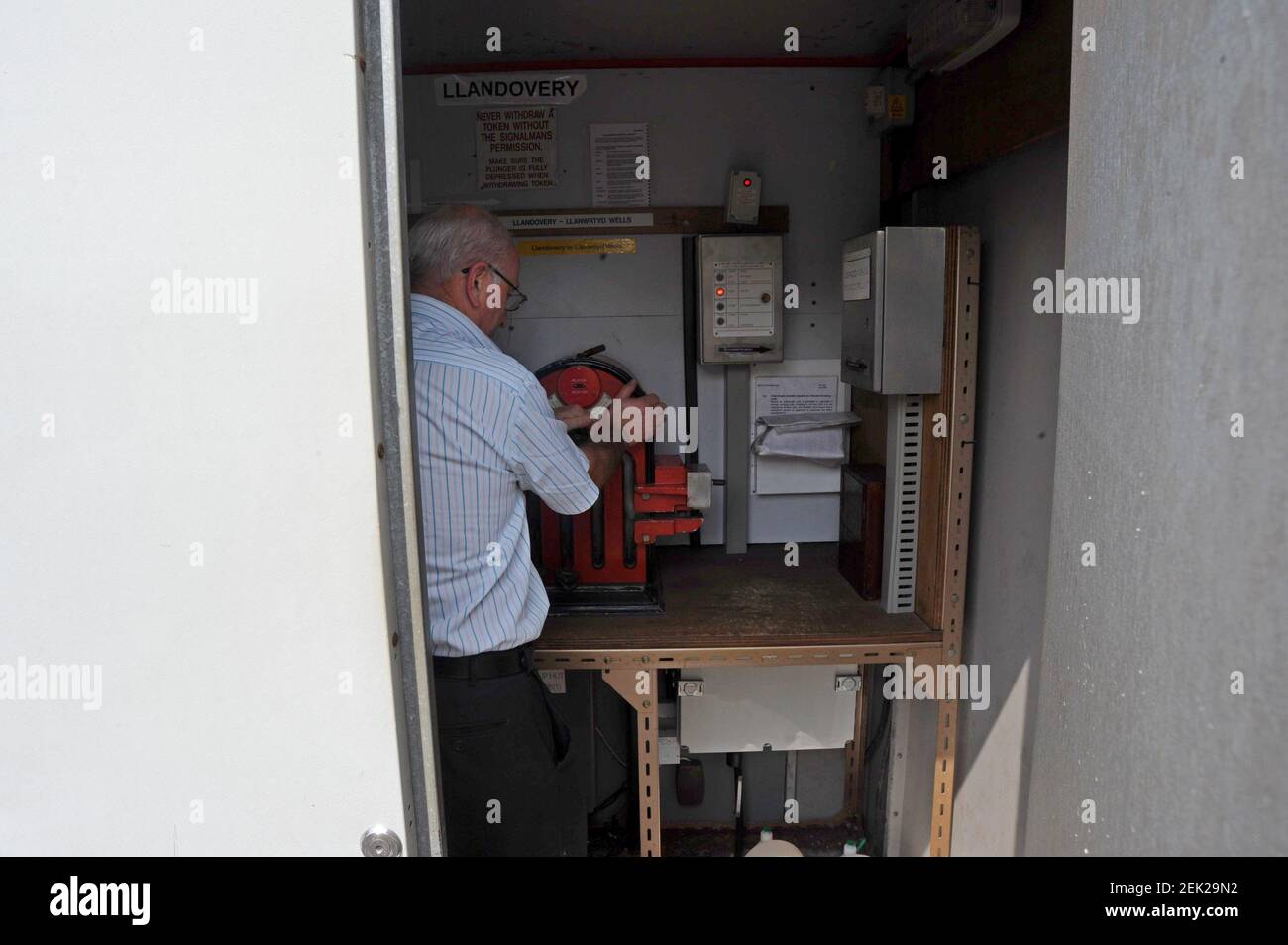 Der Zugfahrer holt einen Token mit einer Linie am Token-Automaten an der Llandovery Station, Heart of Wales Line, ab Stockfoto