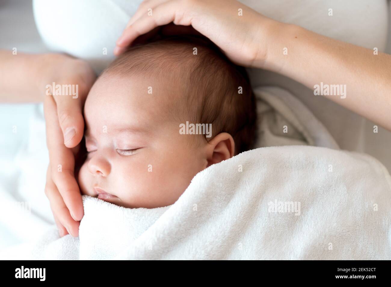 Nahaufnahme Porträt von Mutter mit neugeborenem Baby auf weißem Hintergrund Kopie Raum. Junge nette kaukasische Frau schwarz behaart halten Kind in den Armen Mutterschaft Stockfoto