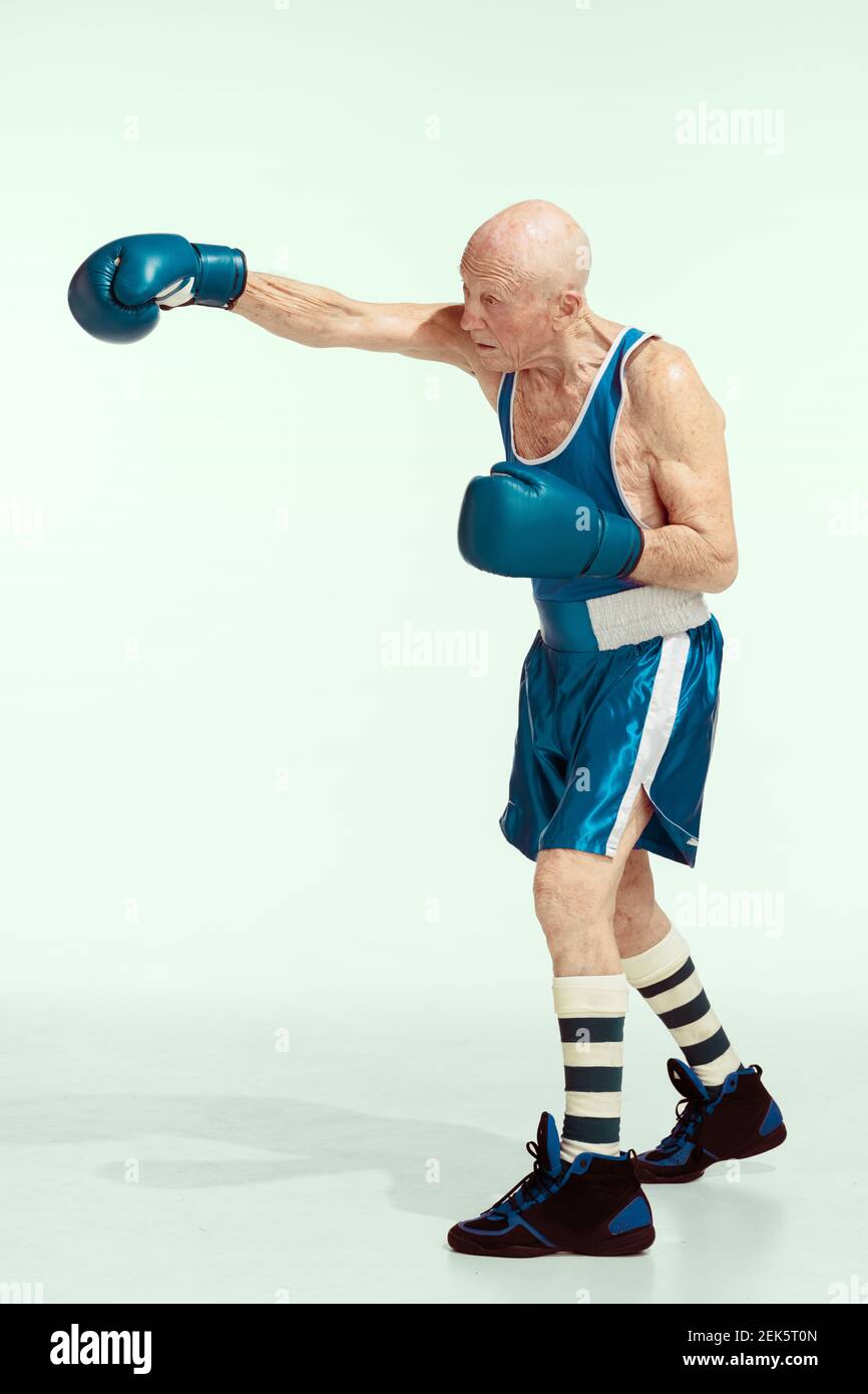 Stanzen. Senior Mann trägt Sportbekleidung Boxen auf Studio Hintergrund. Kaukasisches männliches Modell in guter Form bleibt aktiv und sportlich. Konzept von Sport, Aktivität, Bewegung, Wohlbefinden. Copyspace, Anzeige. Stockfoto