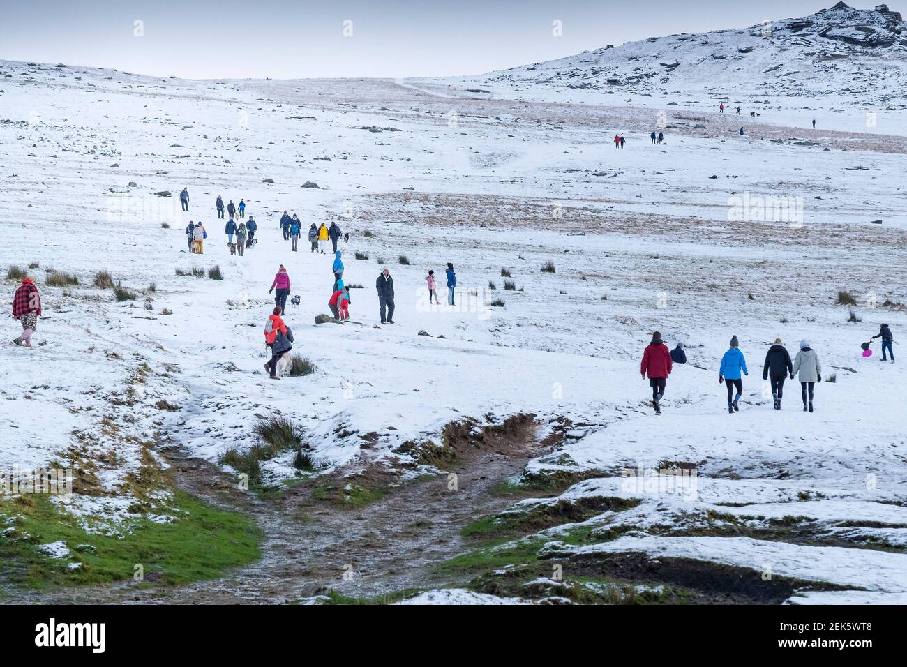 Menschen genießen einen Spaziergang im Schnee auf Rough Tor auf Bodmin Moor in Cornwall. Stockfoto