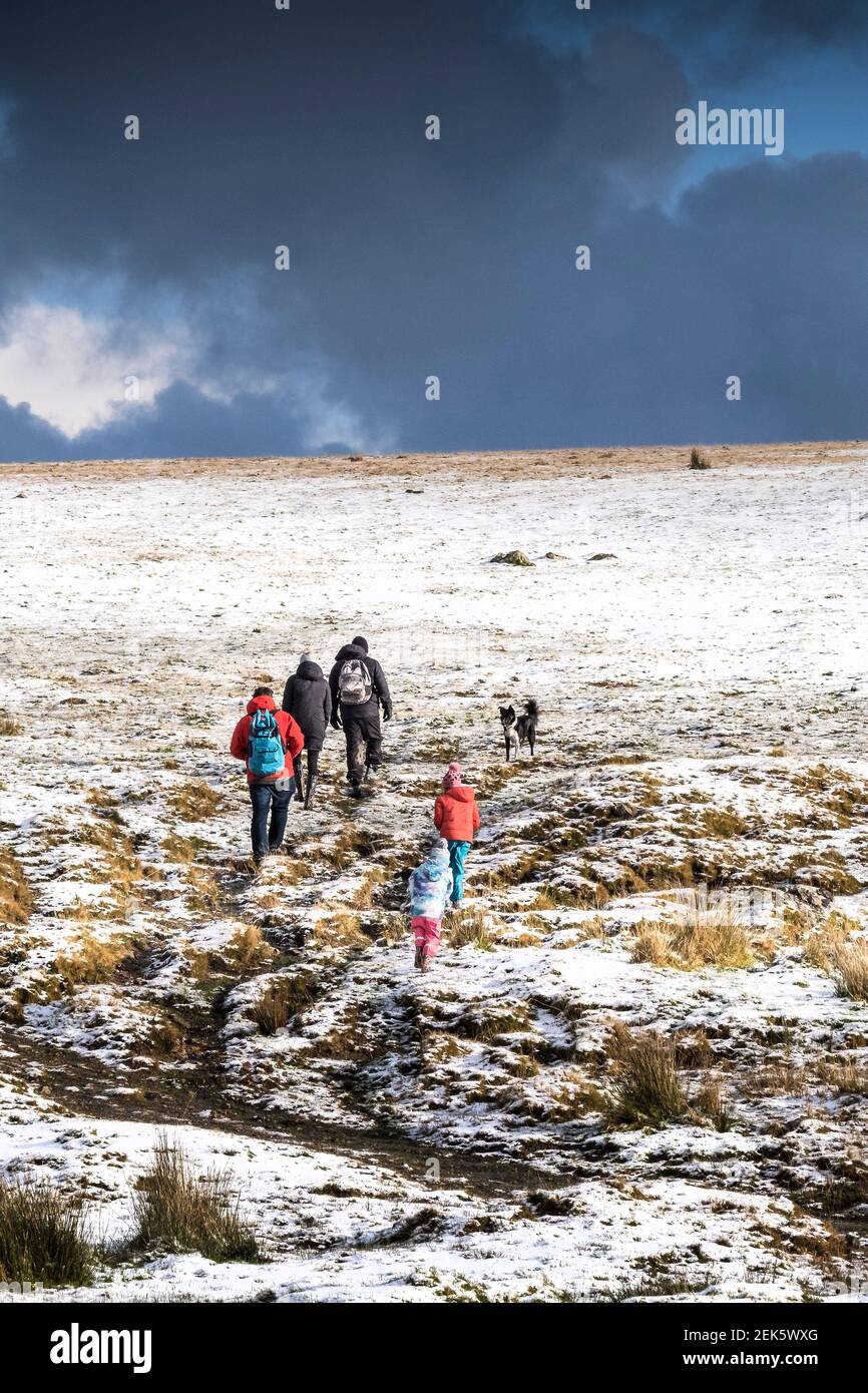 Eine Familie genießt einen Spaziergang im Schnee auf dem wilden rauen Tor auf Bodmin Moor in Cornwall. Stockfoto