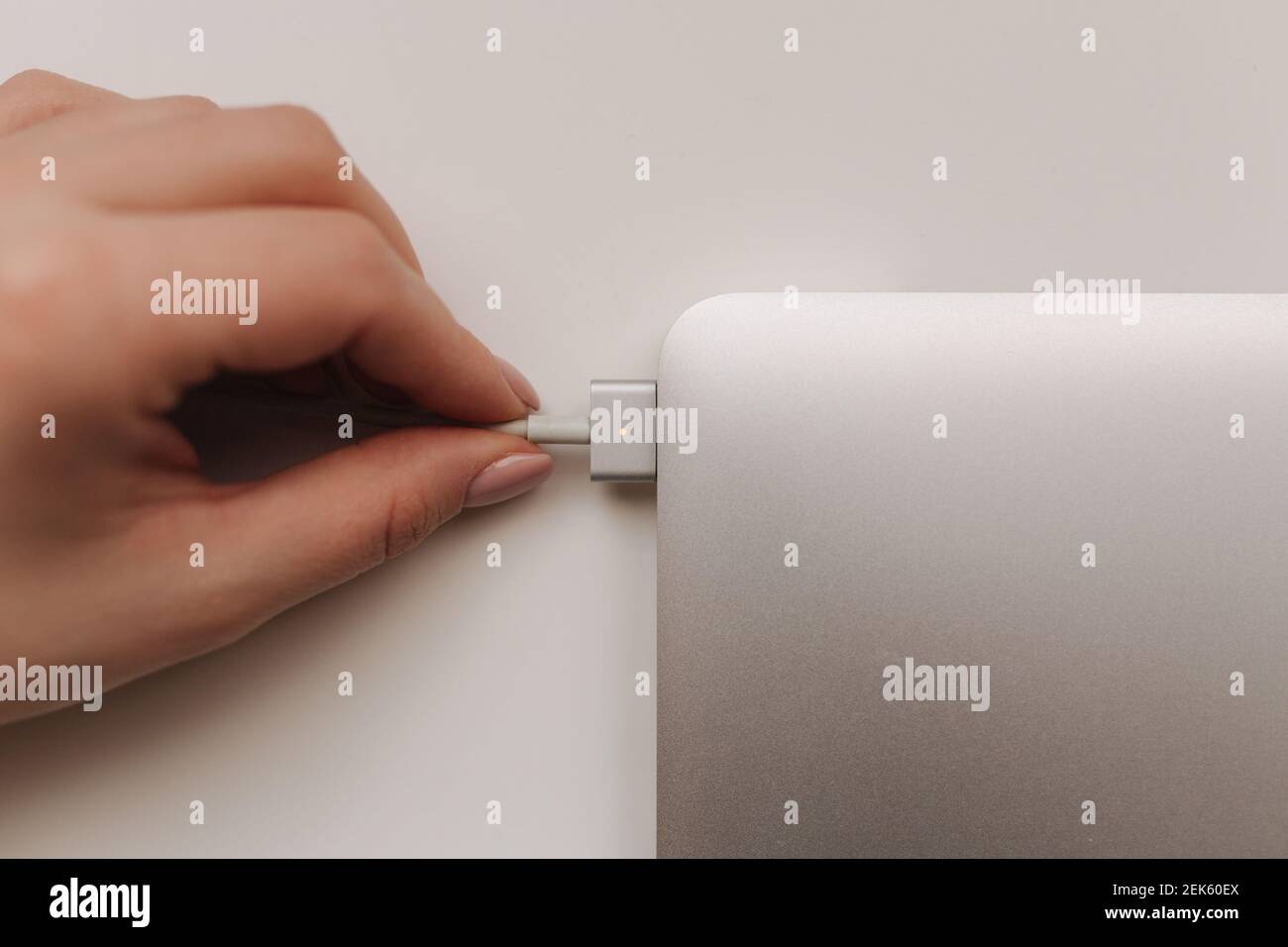 Draufsicht der weiblichen Hand, die den Netzstecker des pc-Notebooks hält. Notebook-Leistung Stockfoto