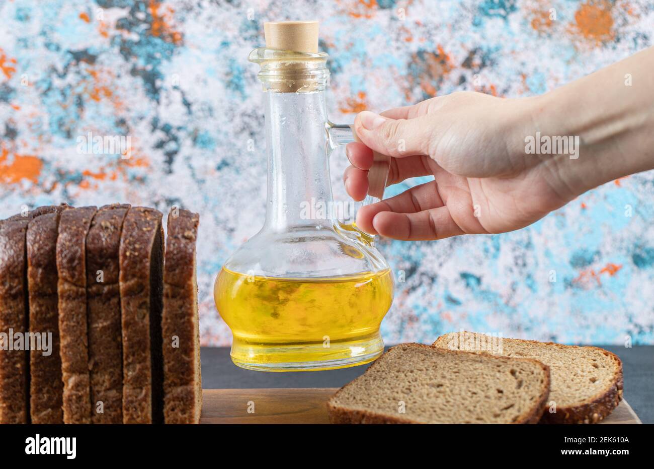 Hand hält eine Flasche Öl auf einem bunten Hintergrund Stockfoto