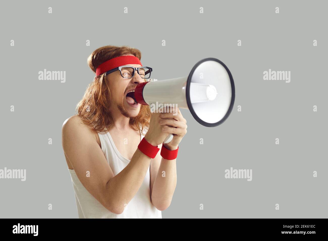 Lustige junge Mann in Retro-Sportbekleidung schreien in Megaphon isoliert Auf grauem Hintergrund Stockfoto