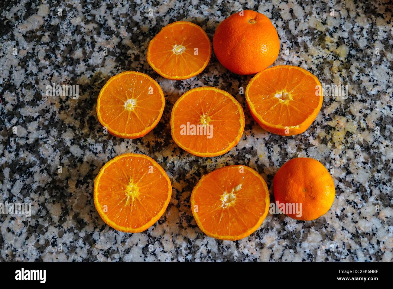 Frische Orangen bereit zum Quetschen, um Orangensaft auf der Arbeitsfläche aus Granit zu machen. Stockfoto