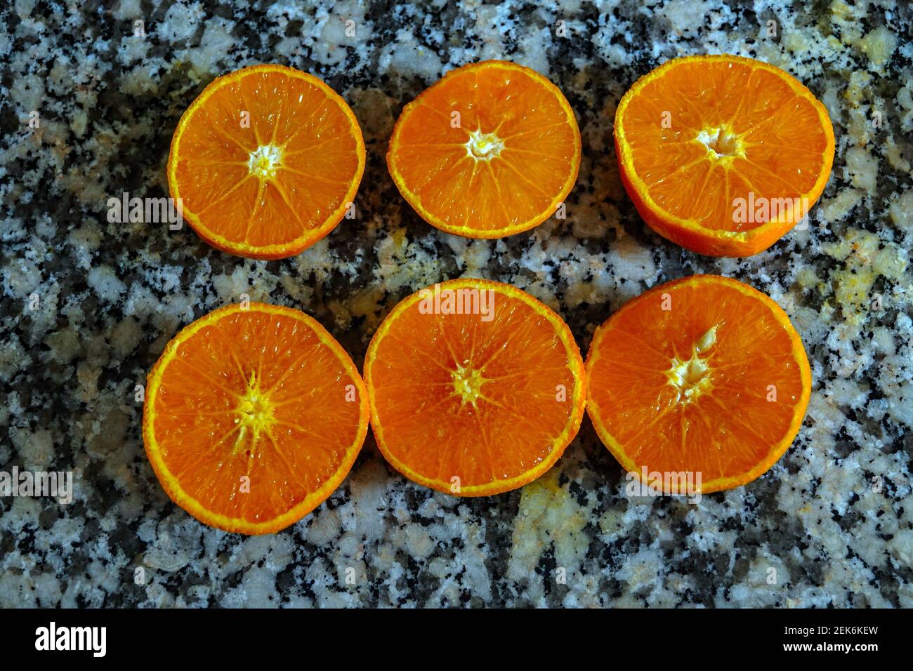 Frische Orangen bereit zum Quetschen, um Orangensaft auf der Arbeitsfläche aus Granit zu machen. Stockfoto