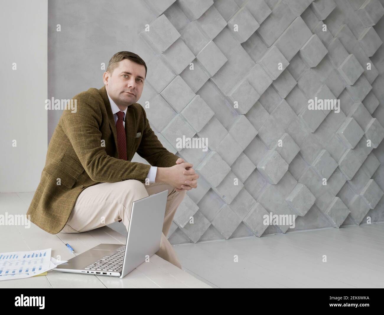 Porträt eines Geschäftsmannes, der in die Kamera schaut. Laptop und Papier. Leerer Raum. Stockfoto
