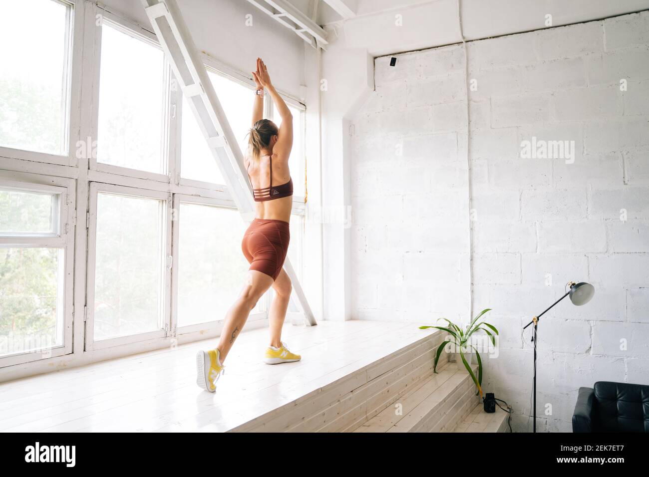 Flexible junge Frau mit athletischen Körper trägt Sportkleidung tun vorne ein Bein Schritt Ausfallschritt. Stockfoto