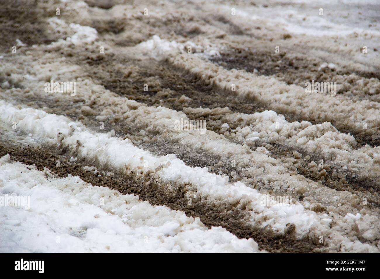 Schmutziger Schnee gemischt mit sauberem auf der Straße. Schnee schmelzen mit Sand darauf. Stockfoto