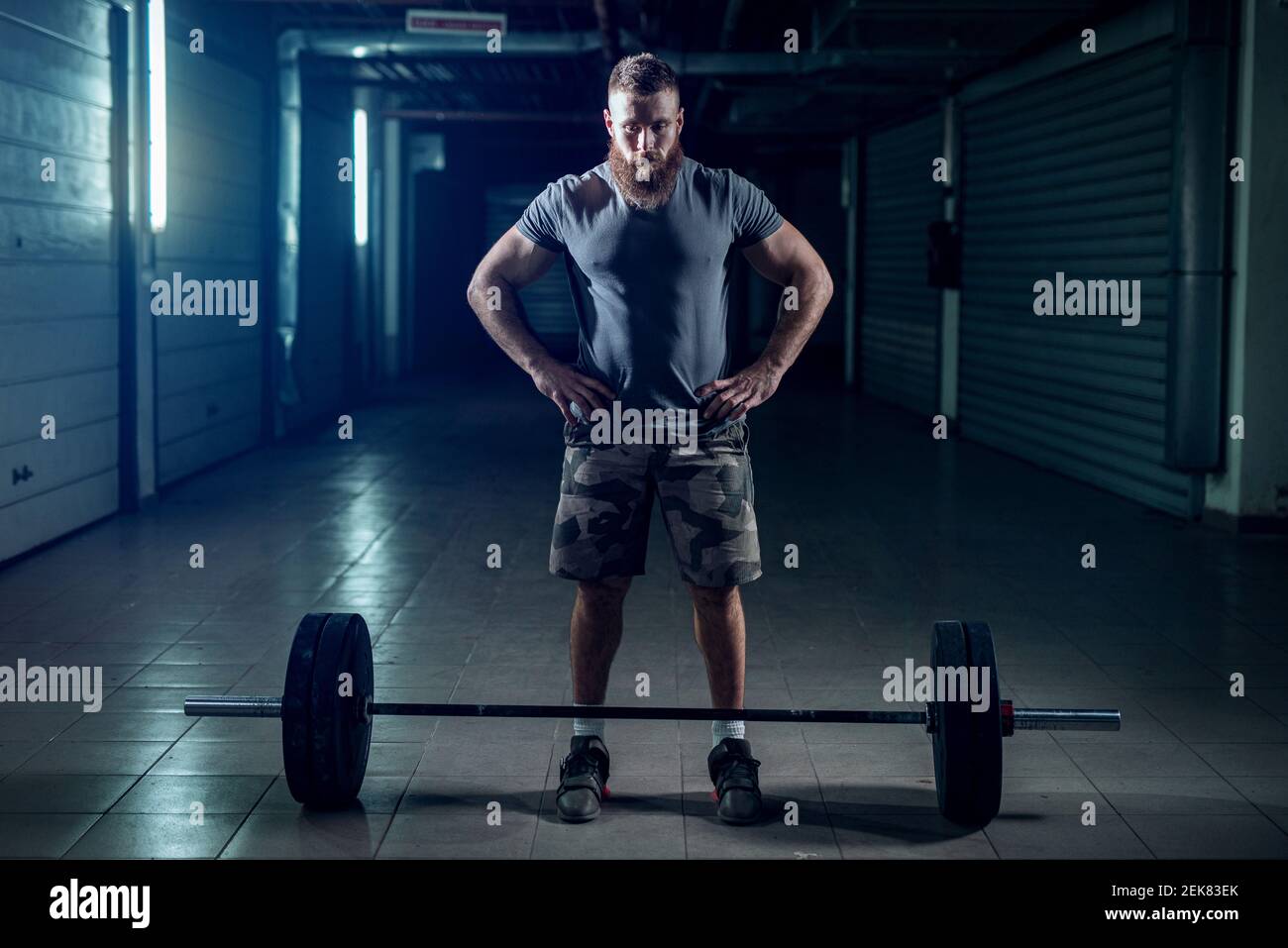 Bild von starken sportlichen Bodybuilder bereitet ihn selbst für schwere Heben. Stehen vor schwerem Gewicht in dunklen Raum. Stockfoto