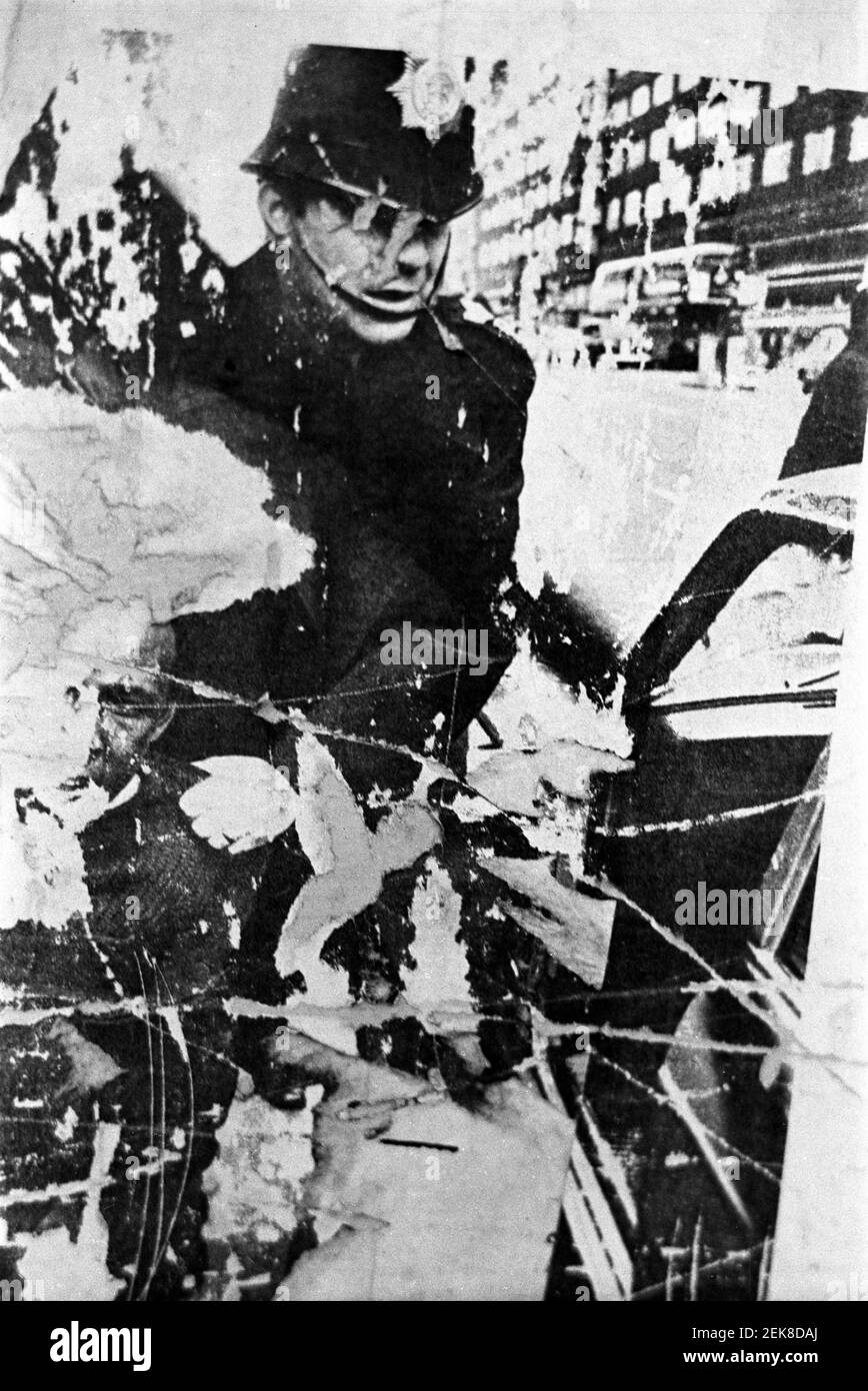 Großbritannien, West London, Notting Hill, 1973. Eine Wand mit alten zerrissenen und zerrissenen Plakaten, die mit einem Bild eines Polizisten aufgeklebt wurden. Stockfoto