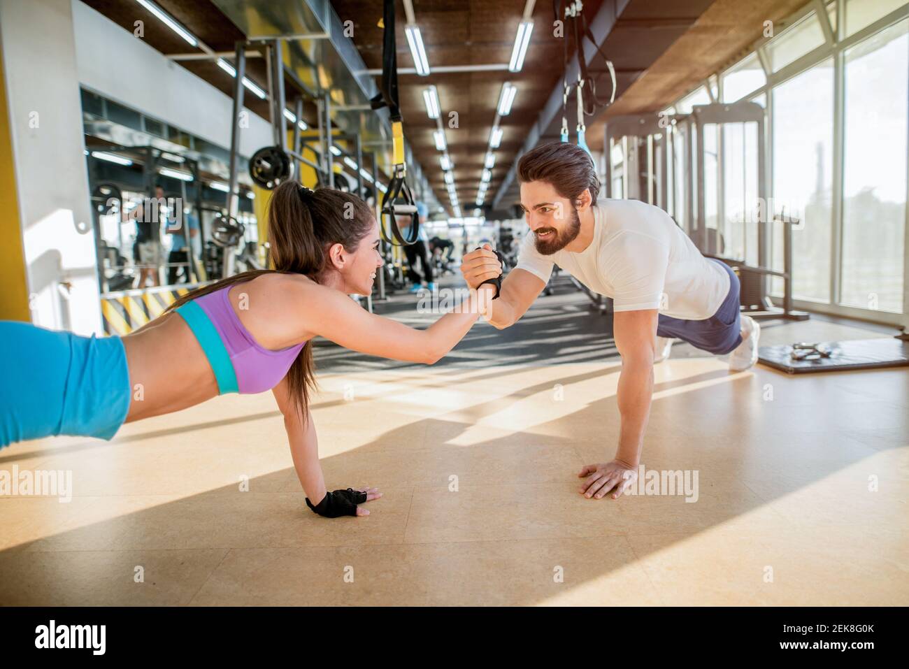 Junges sportliches Paar aus gemeinsam in ein Fitnessstudio. Dabei plank Übungen, während jeder andere Holding für eine Hand. Stockfoto