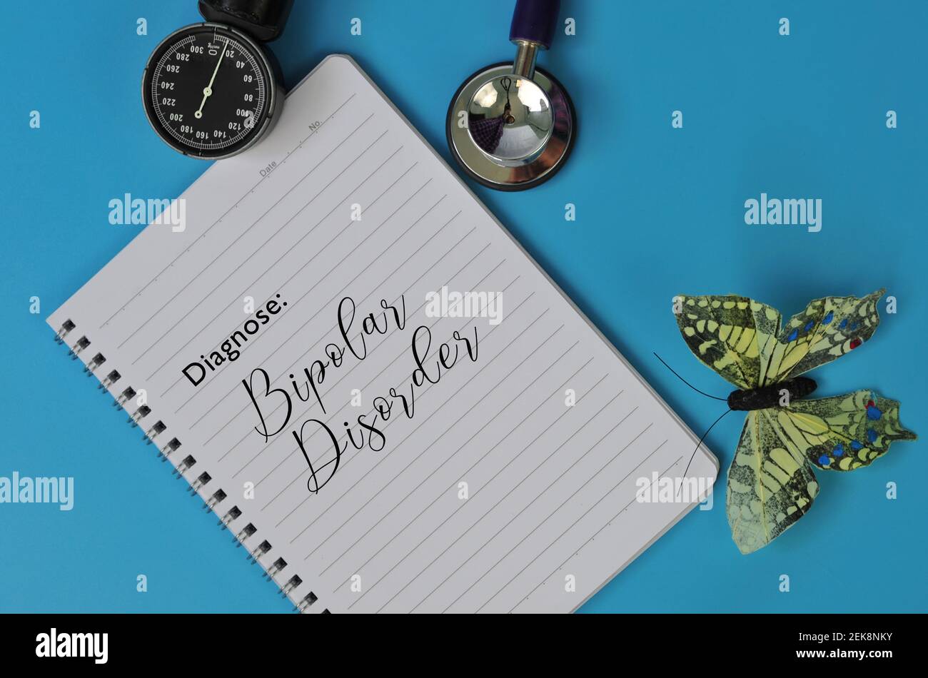 Layout von Stethoskop, Notizbuch und gefälschte Schmetterling mit dem Text DIAGNOSTIZIEREN: BIPOLARE STÖRUNG auf blauem Hintergrund Stockfoto