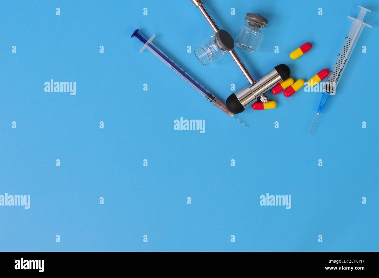 Layout von Reflexhammer, Spritzen, Glasfläschchen und Pillen mit Leerraum für Text auf blauem Hintergrund Stockfoto