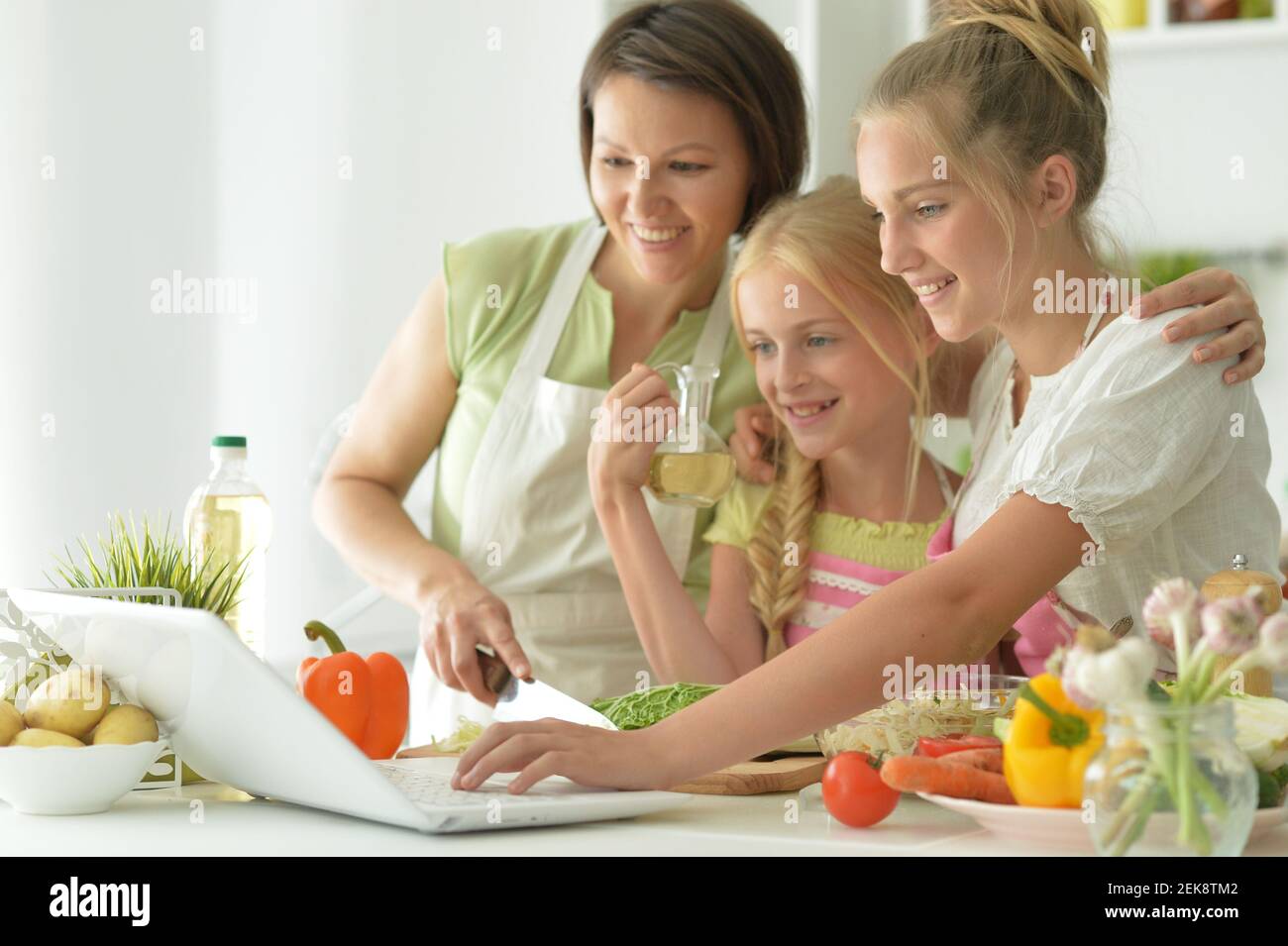 Nette Mädchen mit Mutter Kochen und Blick auf Laptop in Küche Stockfoto