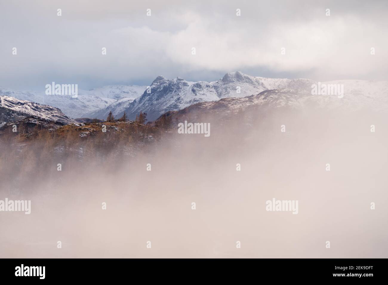 Schneebedeckte Bergkette in einer nebligen majestätischen Winterlandschaft. Langdale Pikes, Lake District, England. Stockfoto