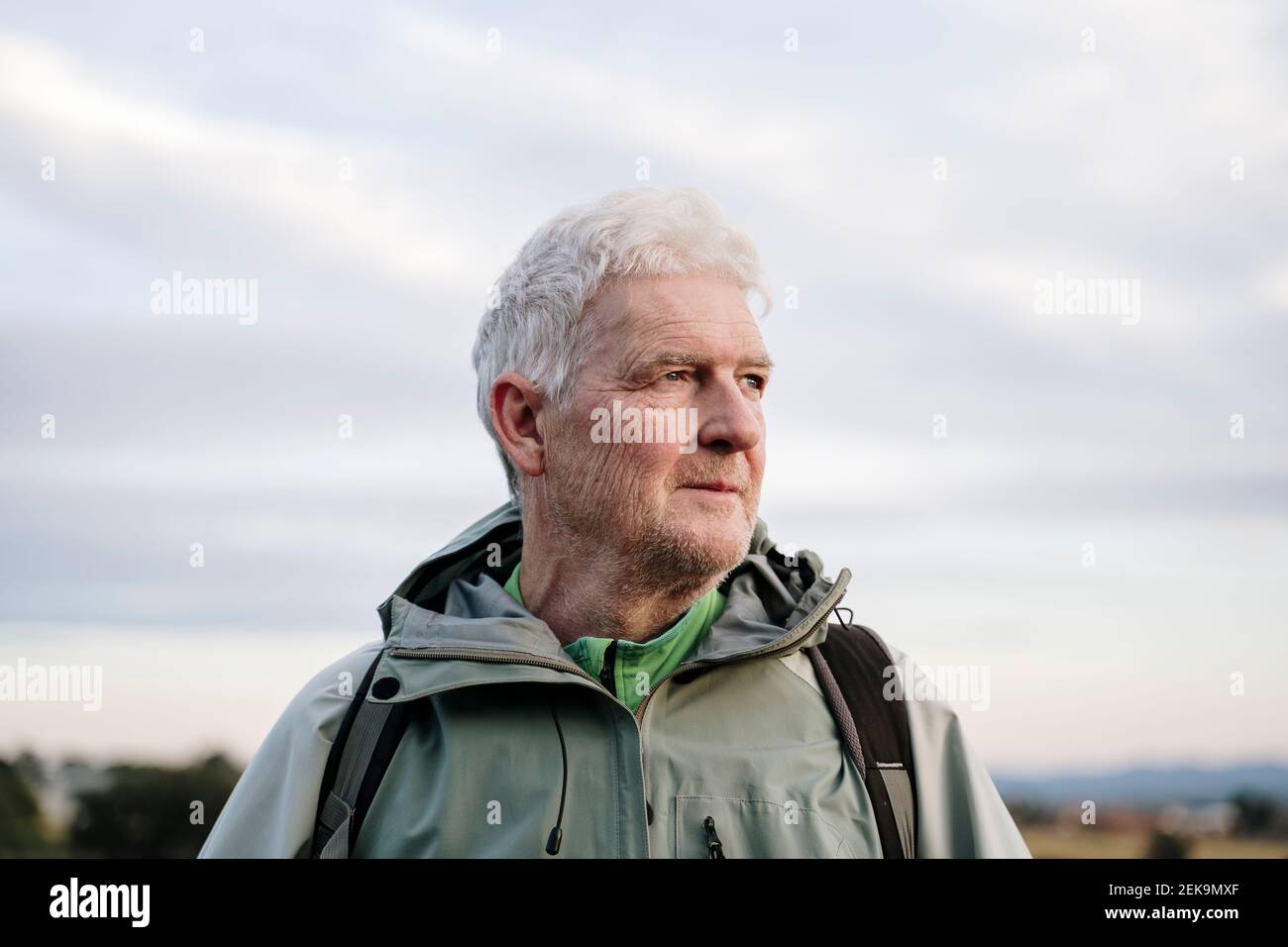 Nachdenklicher älterer Wanderer, der vom Himmel absieht Stockfoto