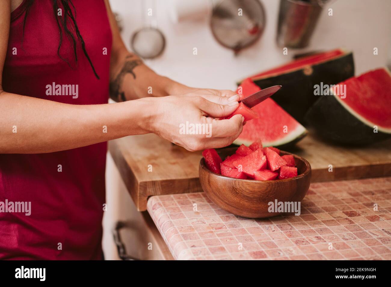 Frau schneid Wassermelone beim Stehen in der Küche zu Hause Stockfoto