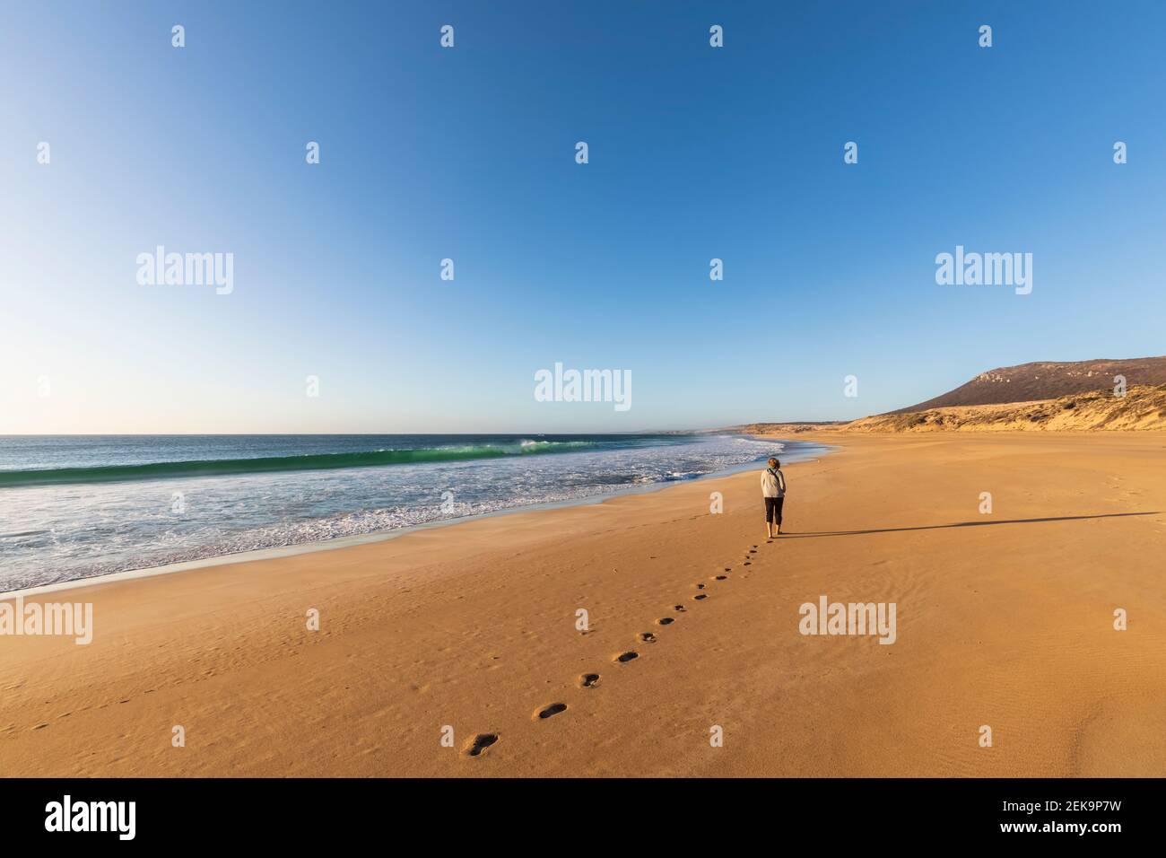 Klarer Himmel über Frau, die alleine am Greenly Beach entlang geht Stockfoto