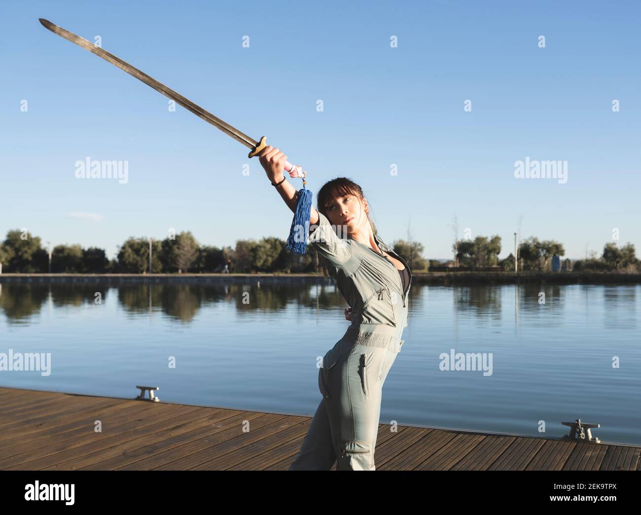 Junge Frau, die im Park durch das Schwert die Kampfkunst übt see an sonnigen Tag Stockfoto
