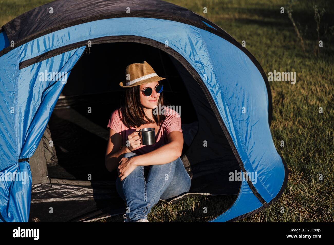 Schöne Frau trägt Sonnenbrille mit Getränk entspannend im Zelt Stockfoto