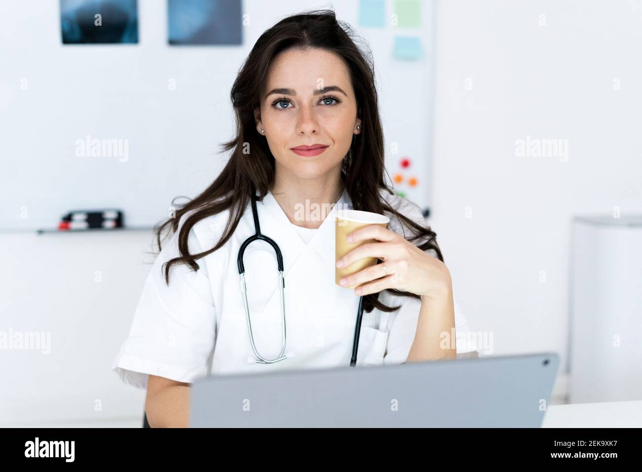 Lächelnd selbstbewusste Ärztin mit Kaffeetasse in der Klinik Stockfoto