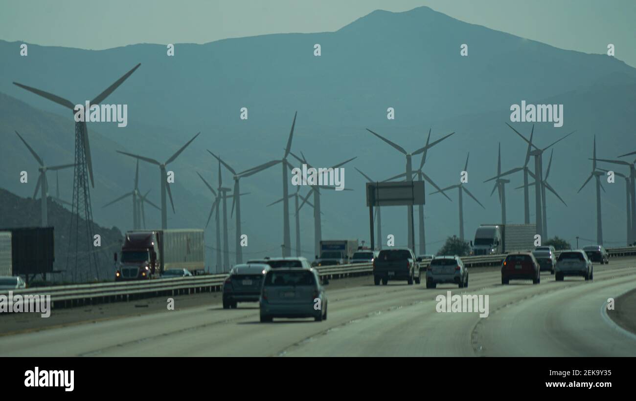 Autos auf einer Autobahn, die an einem Windpark vorbeifahren Trübe Nachmittagsbeleuchtung Stockfoto
