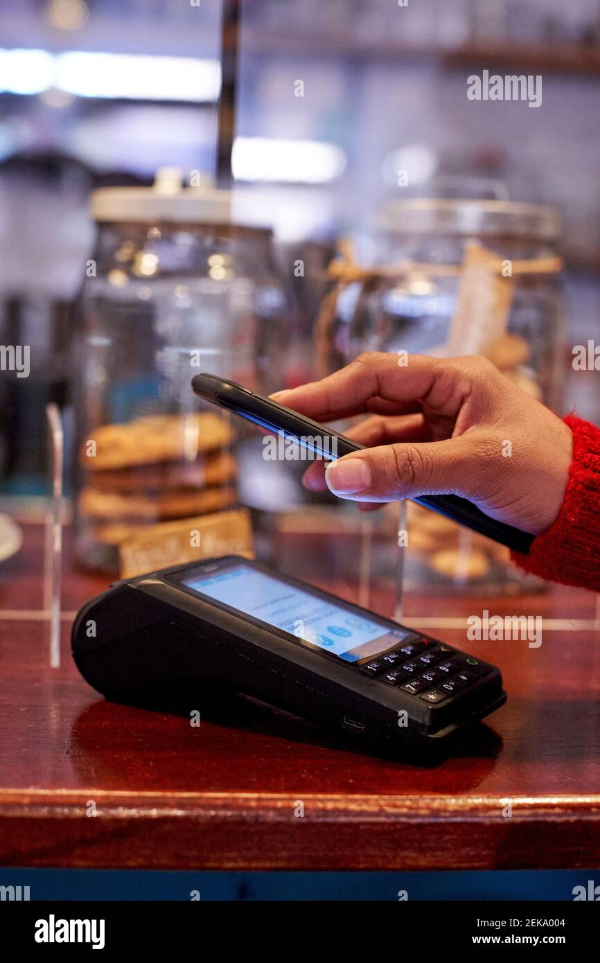 Frau mit Handy für die Zahlung im Café Stockfoto
