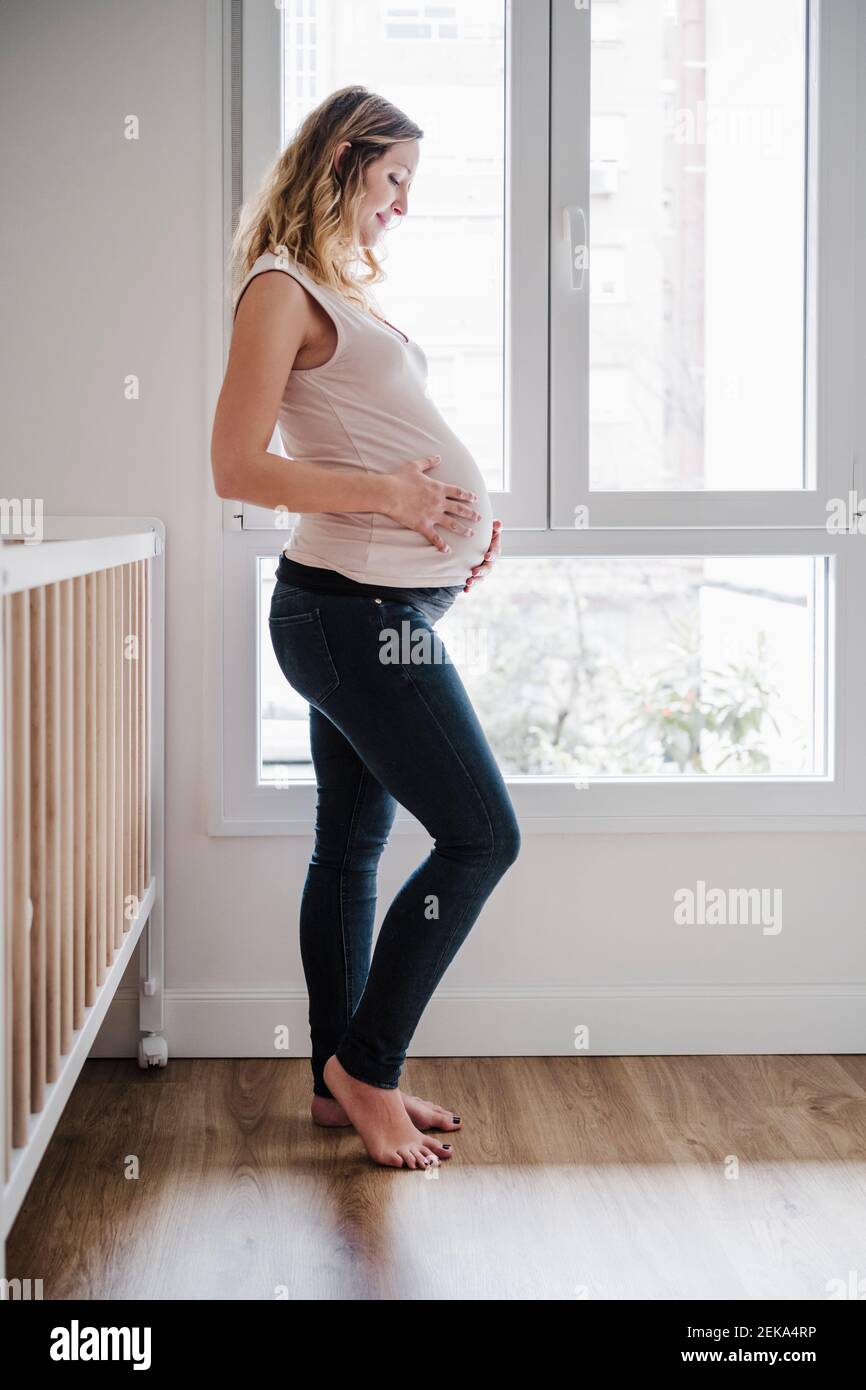 Schwangere Mutter mit den Händen auf dem Bauch antizipierend, während Sie stehen Angezeigt Stockfoto