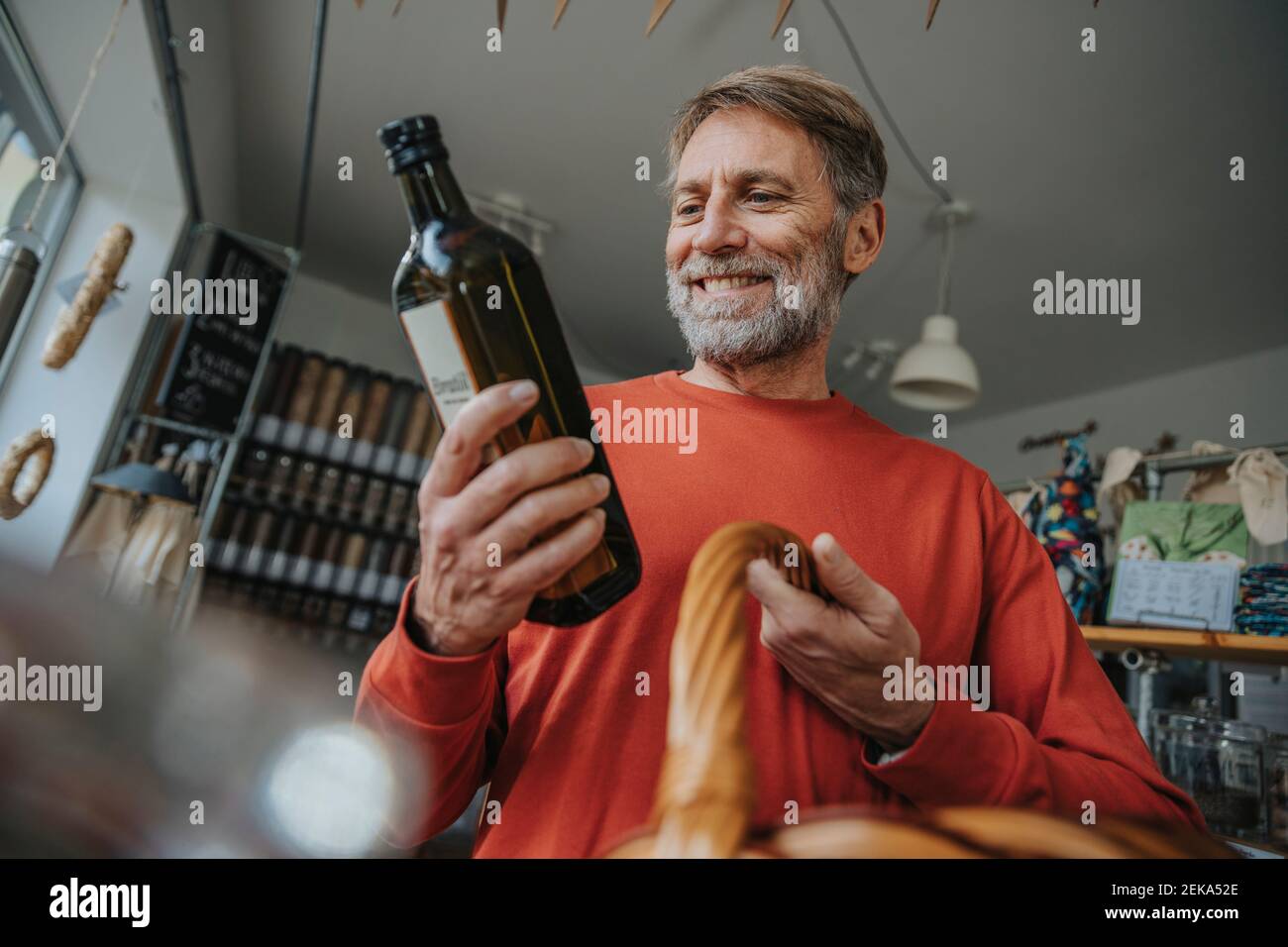 Lächelnder männlicher Kunde hält Getränkeflasche beim Einkaufen in Null Abfalllager Stockfoto