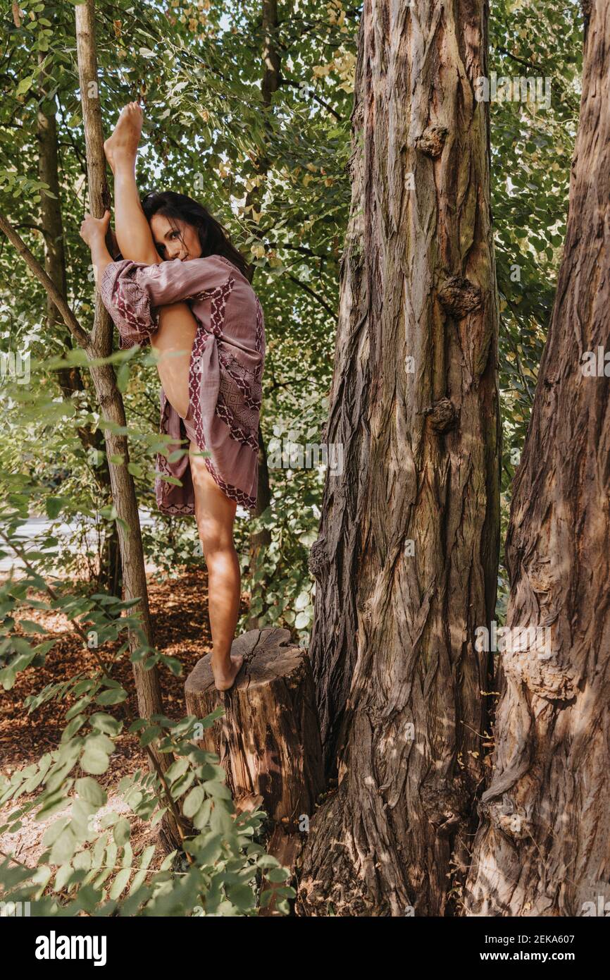 Frau streckt Bein während Yoga im Wald stehen Stockfoto