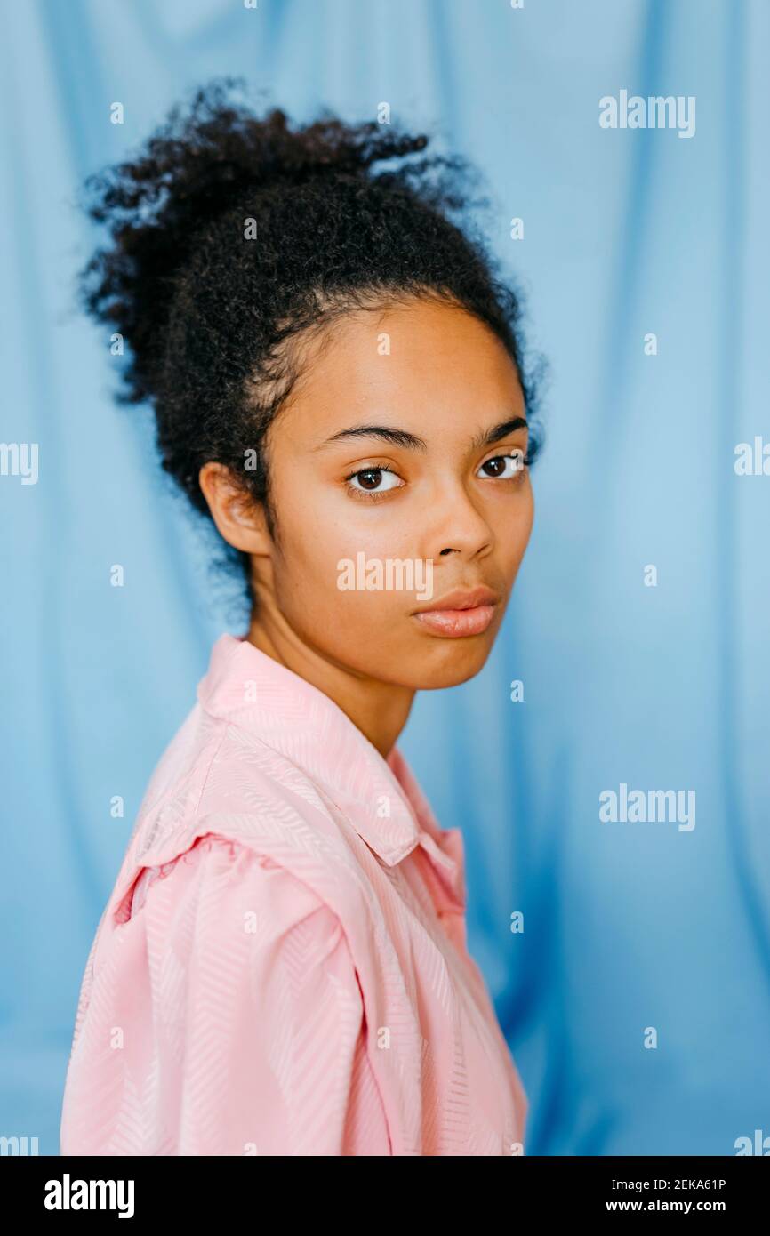 Junge Frau gegen blauen Vorhang Stockfoto