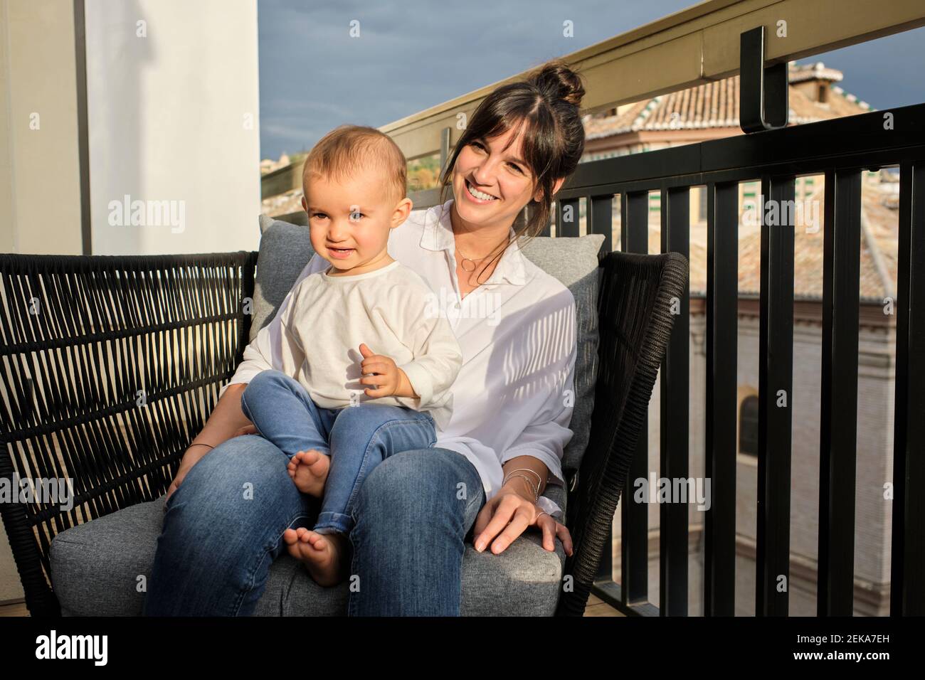 Mutter und Tochter sitzen zusammen im Sessel auf dem Balkon Stockfoto
