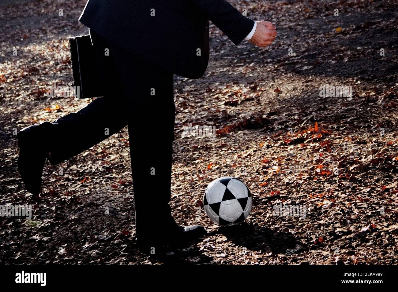 Geschäftsmann spielt mit einem Fußball in einem Park Stockfoto