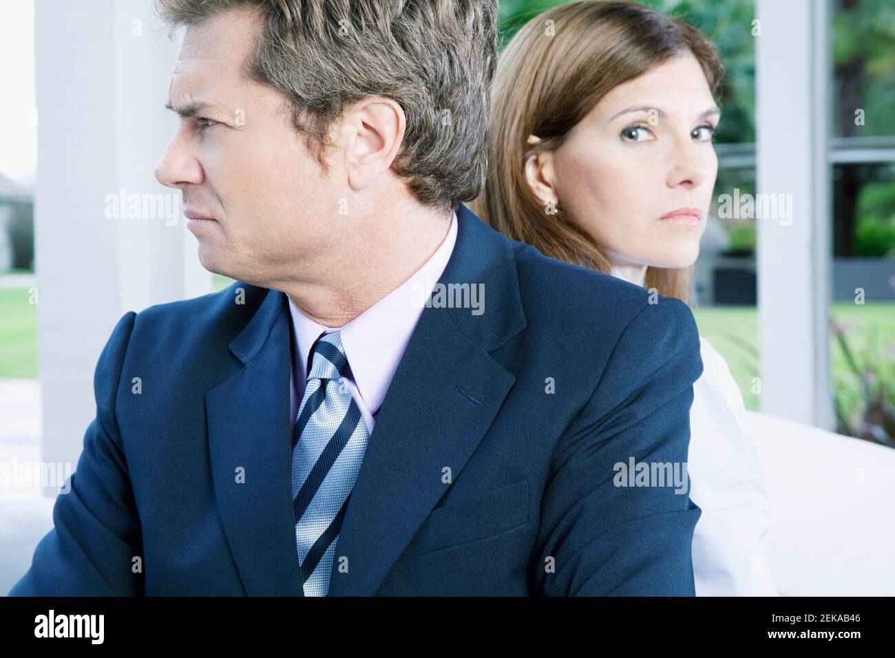 Geschäftsmann und eine Geschäftsfrau, die sich zurück an den Rücken lehnen Stockfoto