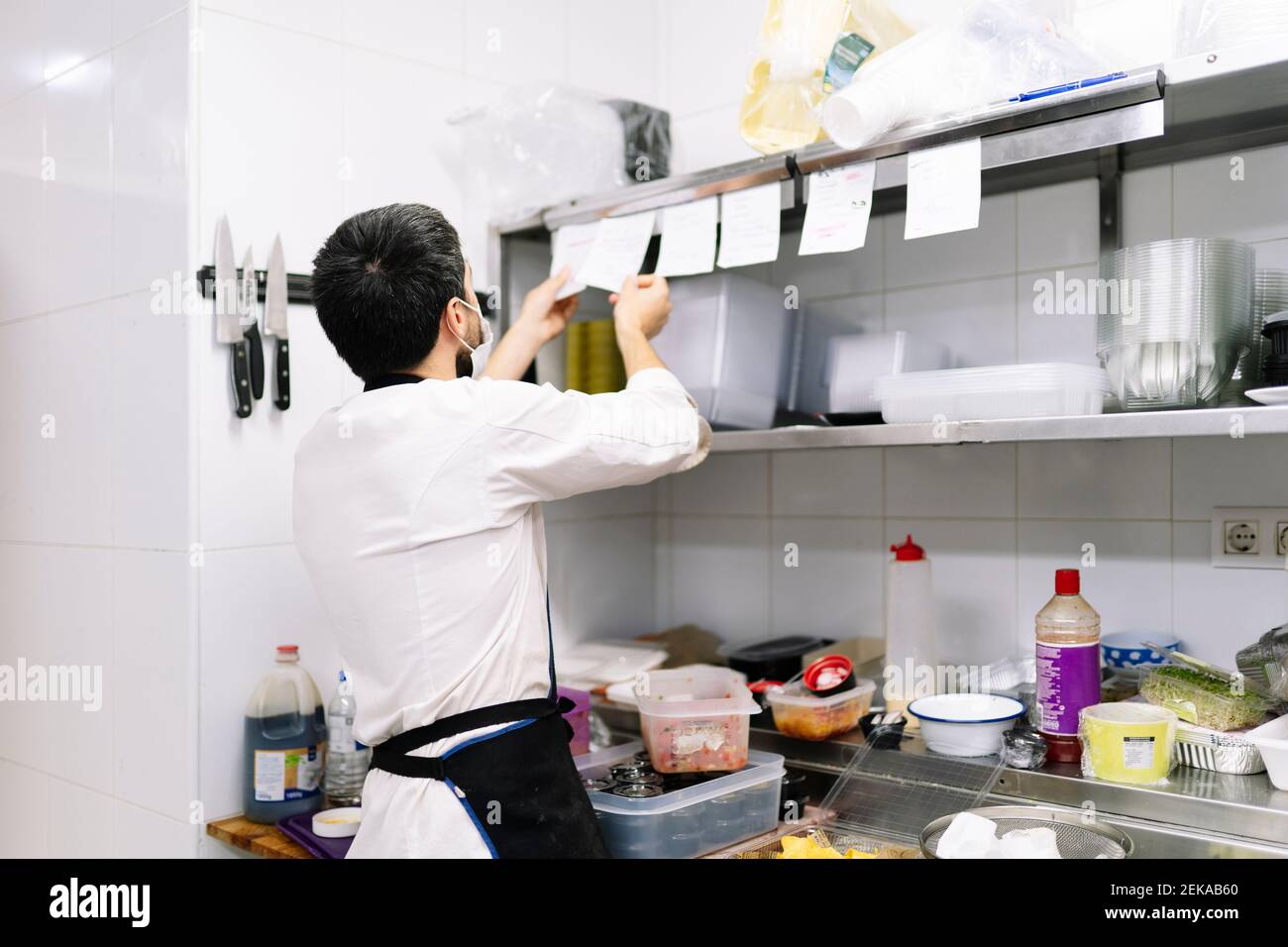 Junger männlicher Koch, der Bestellungen überprüft, während er in der Küche arbeitet Restaurant Stockfoto