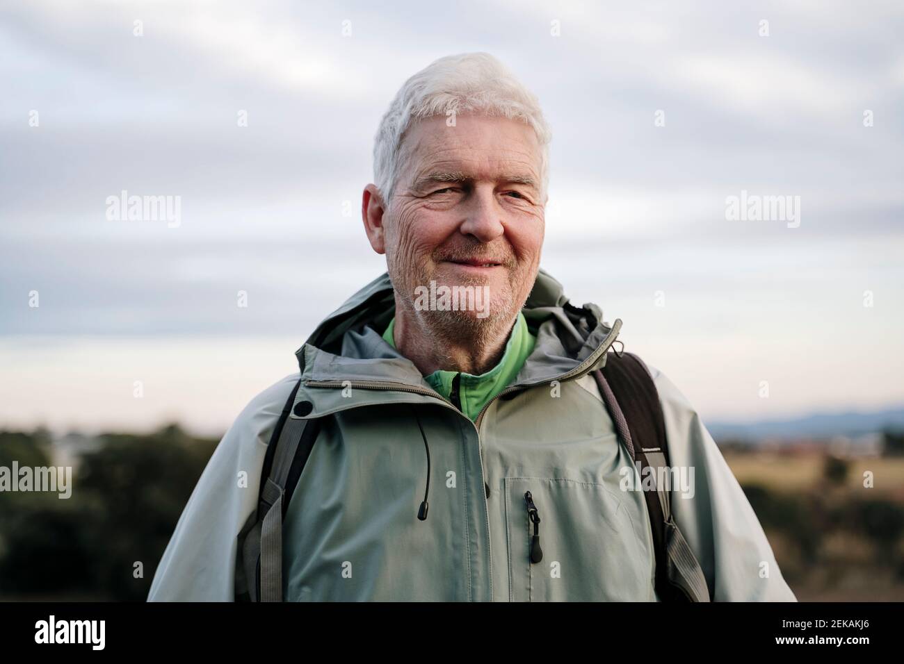 Lächelnder älterer Wanderer, der gegen den Himmel steht Stockfoto