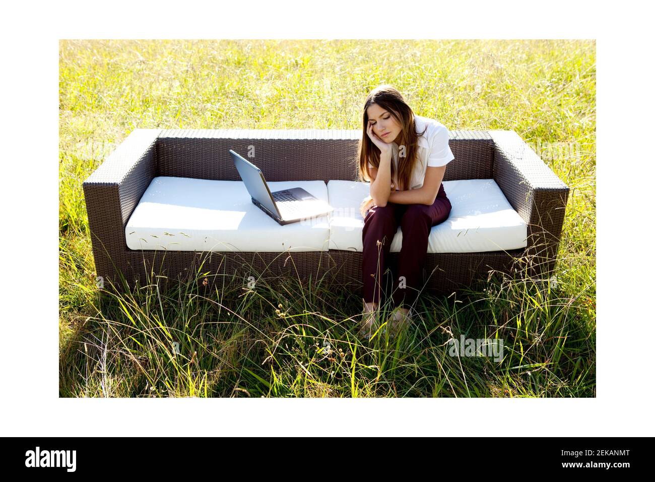 Geschäftsfrau sitzt auf einem Sofa mit einem Laptop in einem Grasland Stockfoto