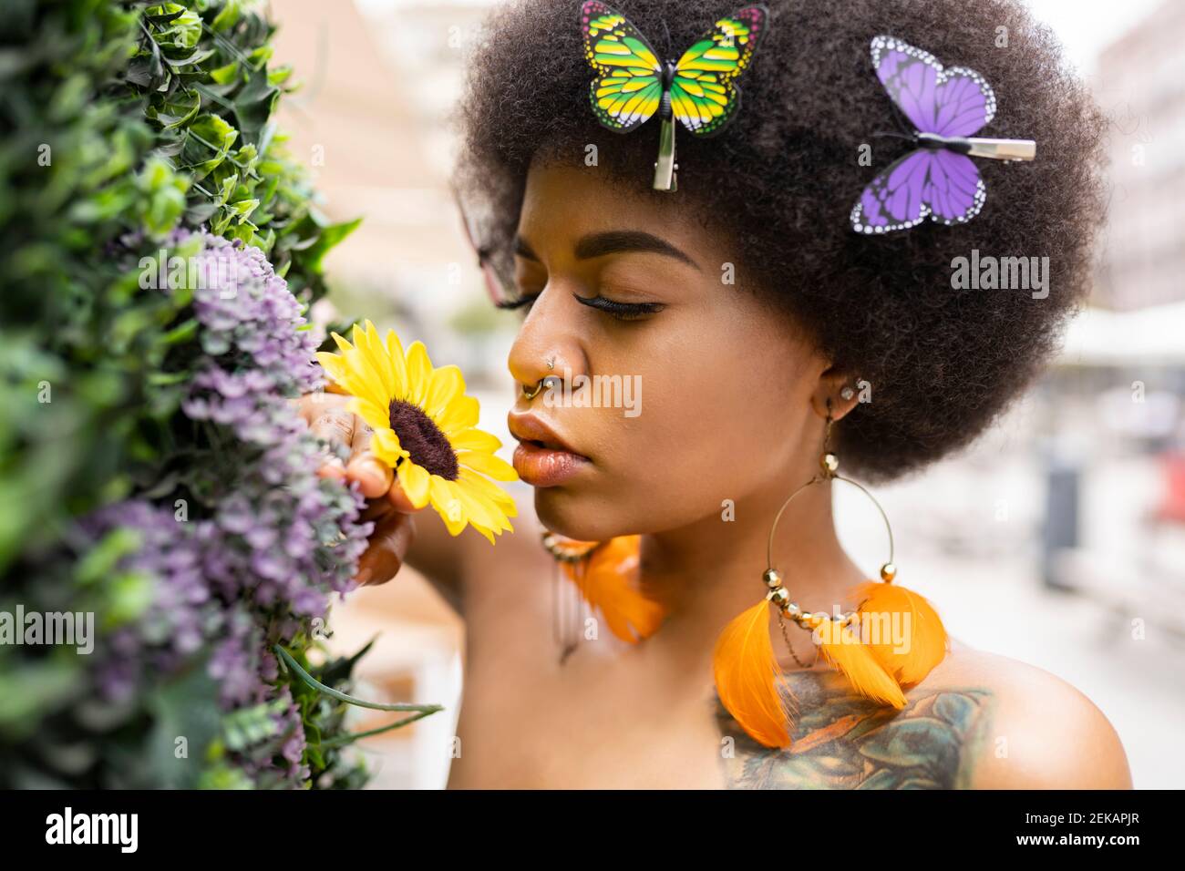 Junge Afro-Frau riecht Blume im Freien Stockfoto