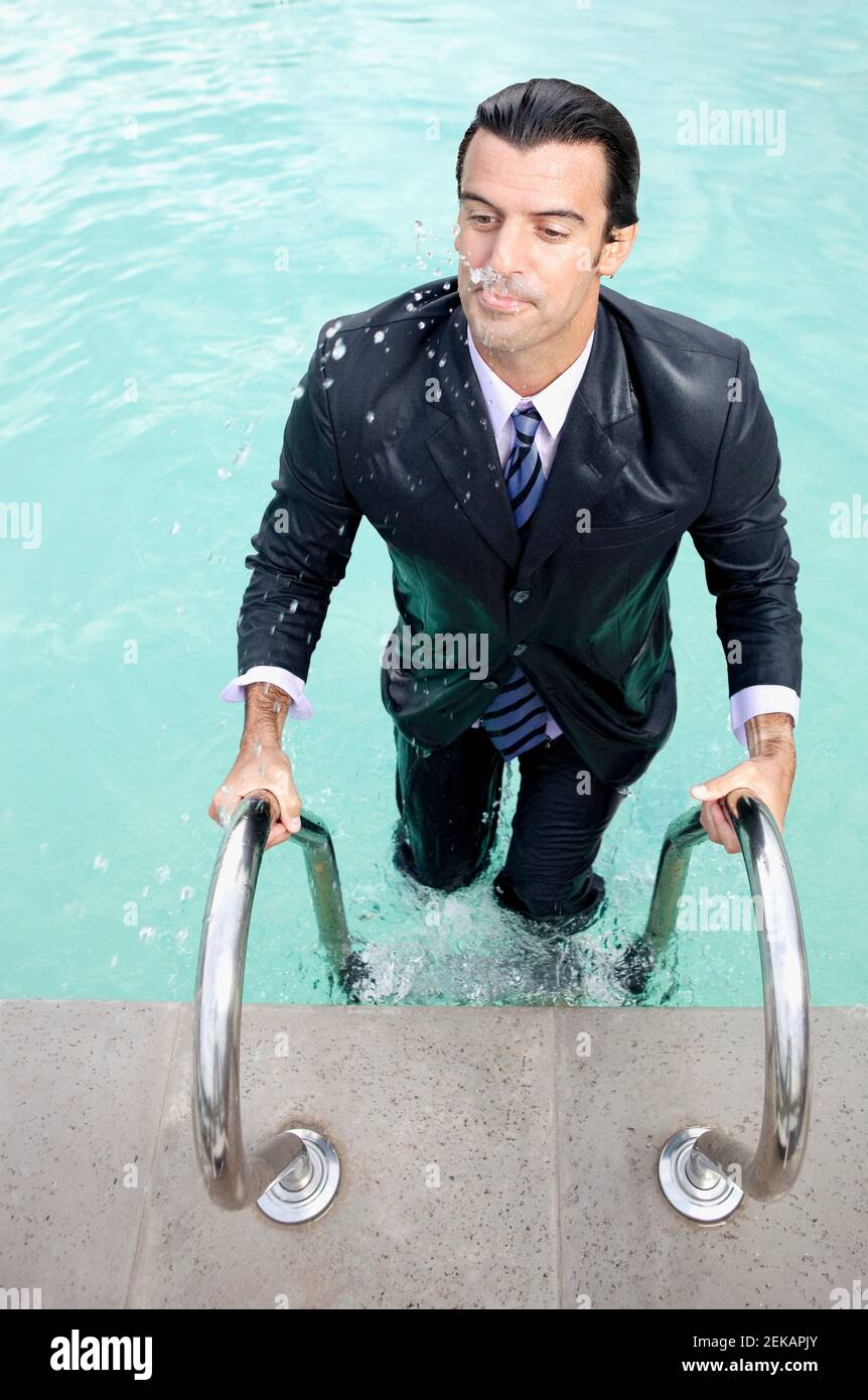 Nasser Geschäftsmann, der aus einem Schwimmbad herauskommt Stockfoto