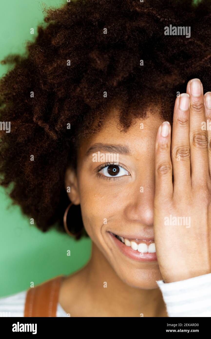 Glückliche Frau, die das halbe Gesicht mit der Hand in der neuen Wohnung bedeckt Stockfoto