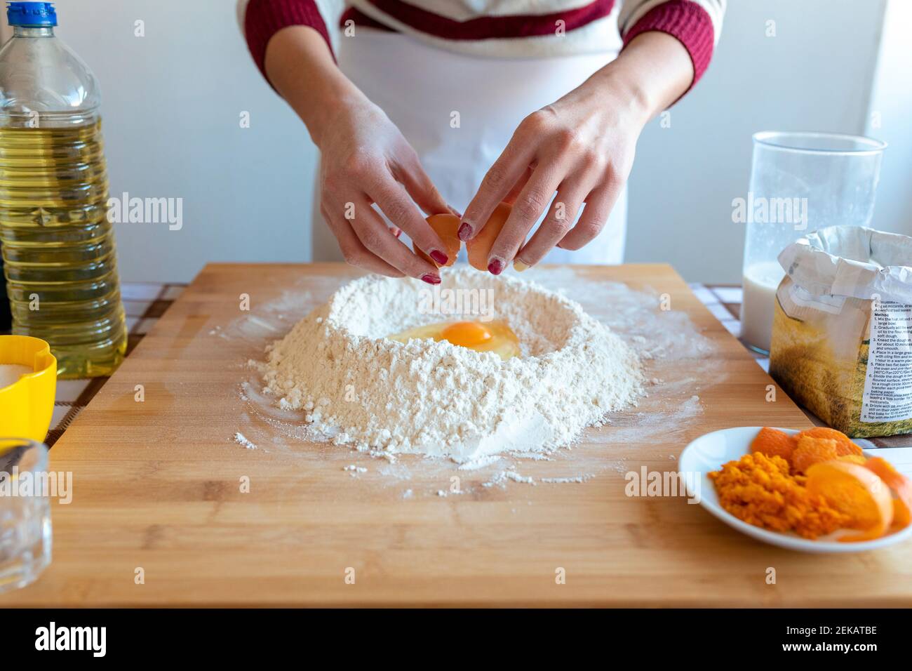 Frau hinzufügen Ei in Mehl in der Küche zu Hause Stockfoto