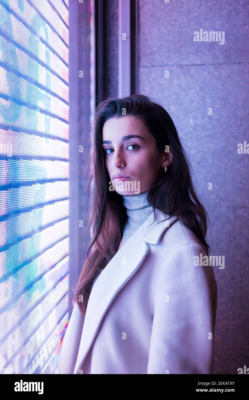 Junge Frau, die durch Fenster Stockfoto