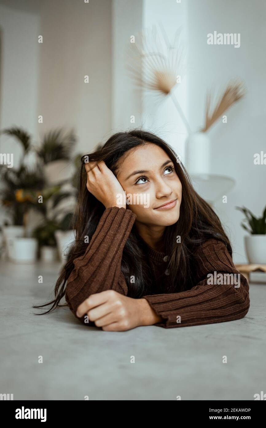 Lächelndes Mädchen mit Kopf in den Händen, während sie sich darauf auflegt Vorne zu Hause Stockfoto