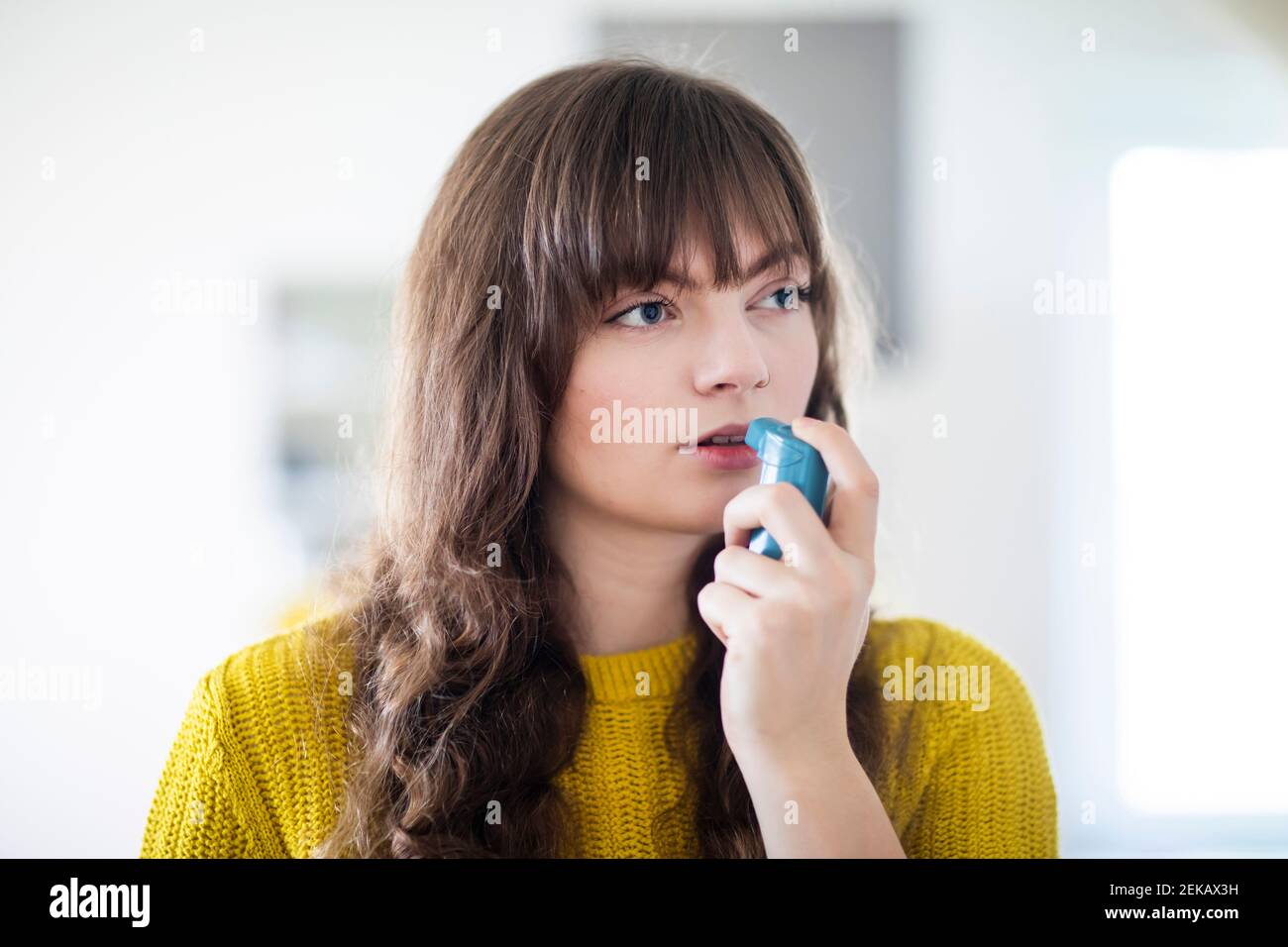 Weibliche Atmung durch Asthma-Inhalator beim wegschauen Stockfoto