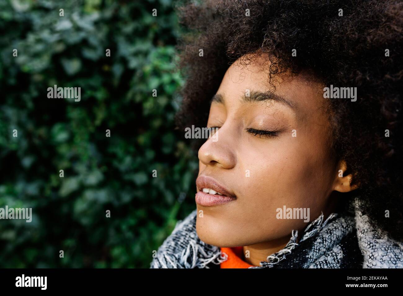 Afro junge Frau mit geschlossenen Augen im Sonnenlicht Stockfoto