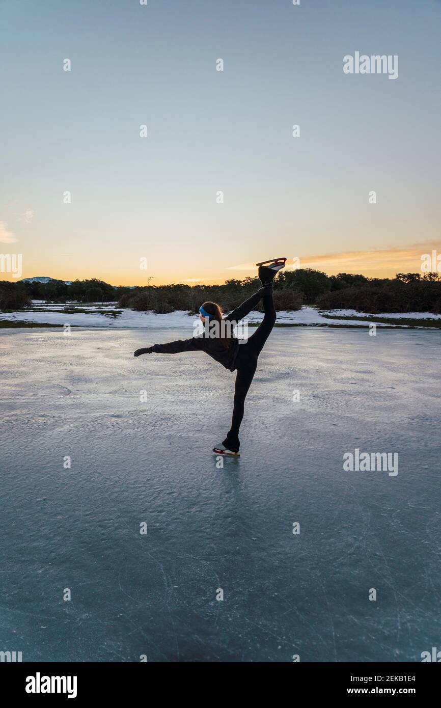 Weibliche Figur Skater üben auf gefrorenen See in der Dämmerung Stockfoto