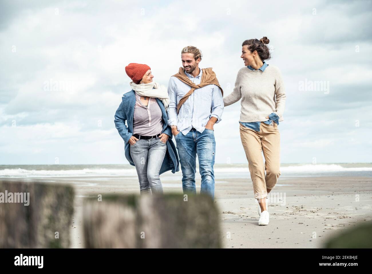 Gruppe von Freunden, die gemeinsam entlang des sandigen Küstenstrandes spazieren Stockfoto