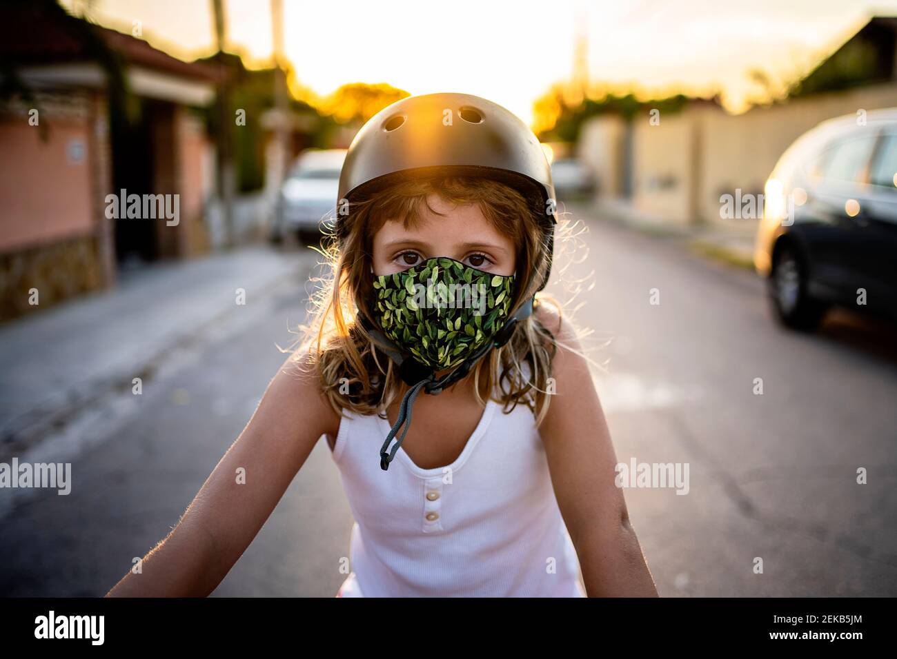 Mädchen trägt Schutzmaske und Helm während des Sonnenuntergangs Stockfoto